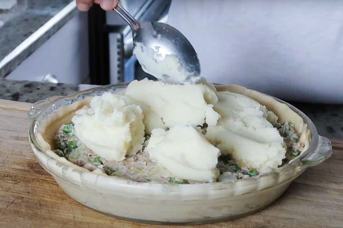 spoon mash potatoes on top of pie